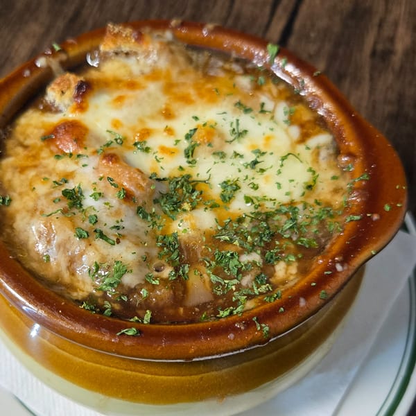 A bowl of Gateway Cafe's French onion soup, topped with melted cheese and fresh parsley.