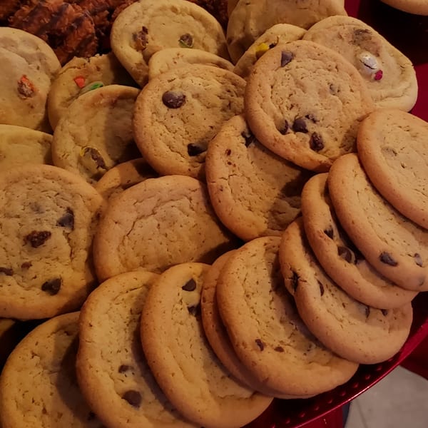 A close-up of a platter filled with various freshly baked cookies, including chocolate chip and M&M cookies.