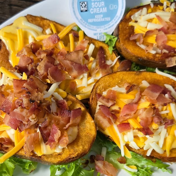 Golden potato skins filled with melted cheese and crispy bacon bits, served with a side of sour cream.